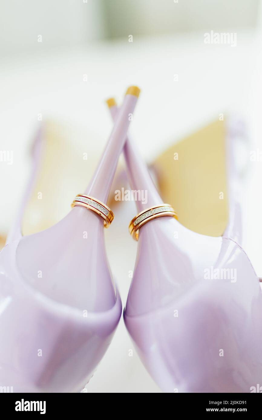 Hochzeit Goldringe auf den Fersen der lila Braut Schuhe. Stockfoto
