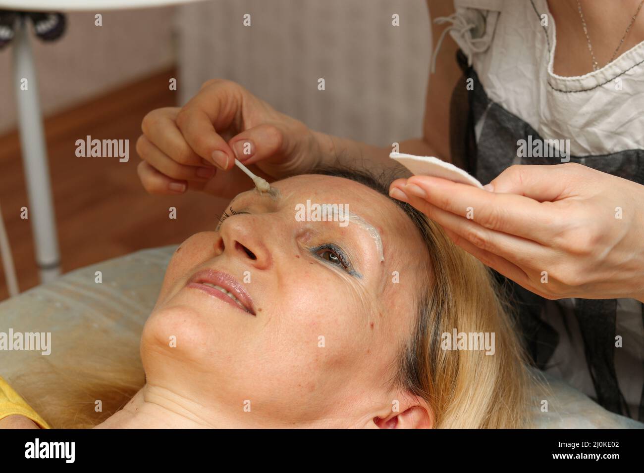 Korrektur und Tönung Henna der Augenbrauen, der Meister wendet sich an die Frau, die auf den Augenbrauen markierend ist Stockfoto
