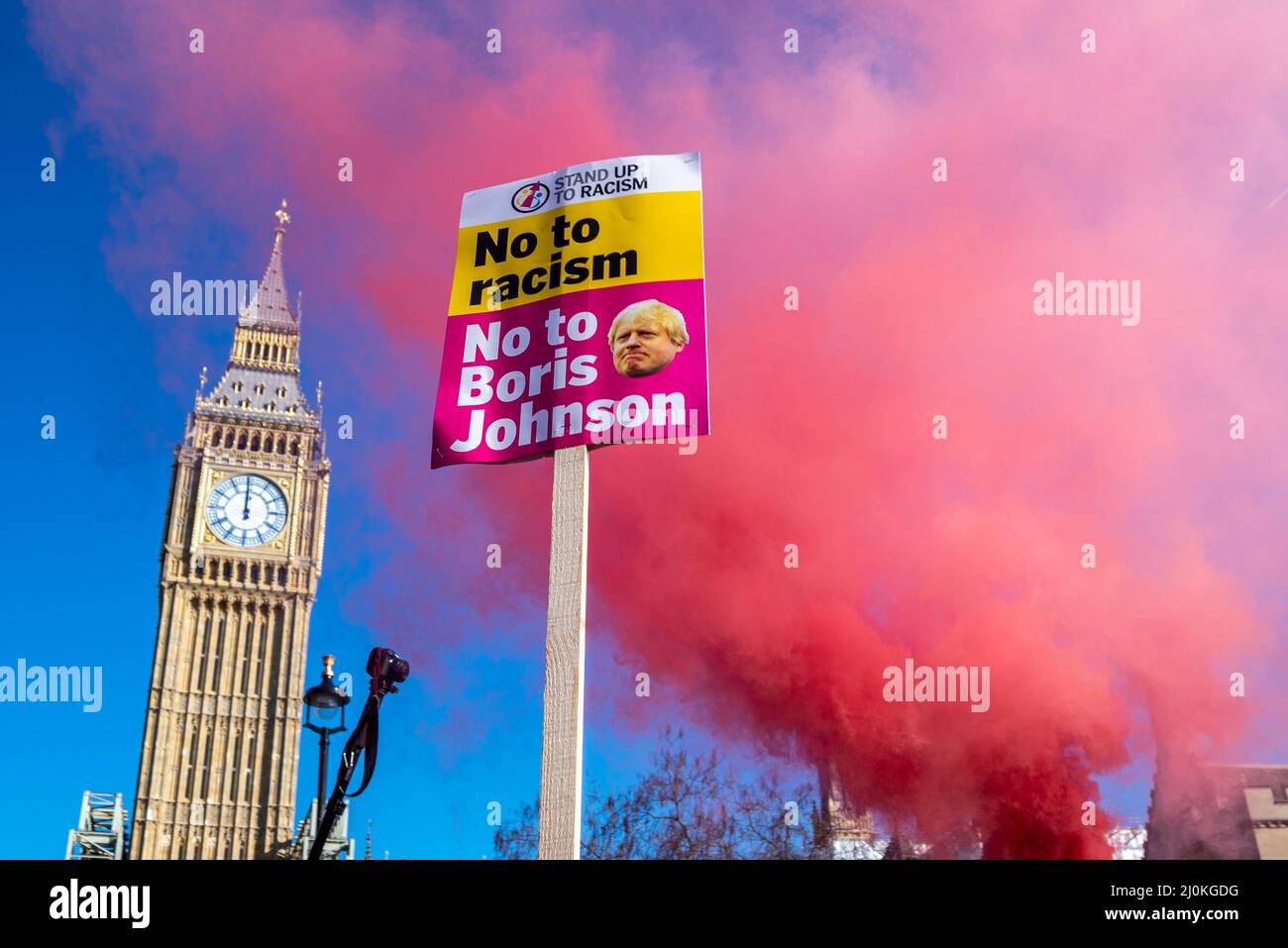 Protest am UN-Tag gegen Rassismus in London. Boris Johnson auf Plakat vorbei Elizabeth Tower of Houses of Parliament mit Rauch Stockfoto