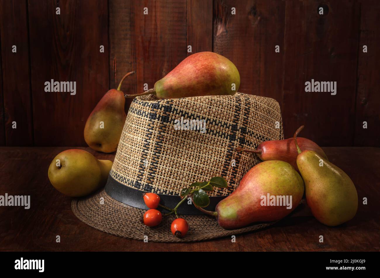 Birnen in loser Schüttung auf einem alten Hut auf einem dunklen Holzhintergrund in rustikalem Stil Stockfoto