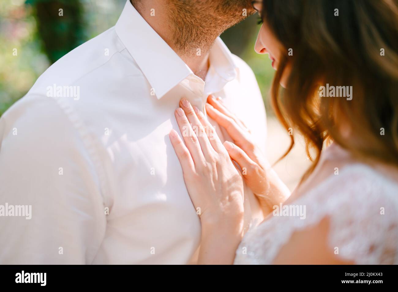 Der Bräutigam umarmt die Braut sanft auf die Stirn, die Braut legt ihre Hände auf die Grooms Brust Stockfoto