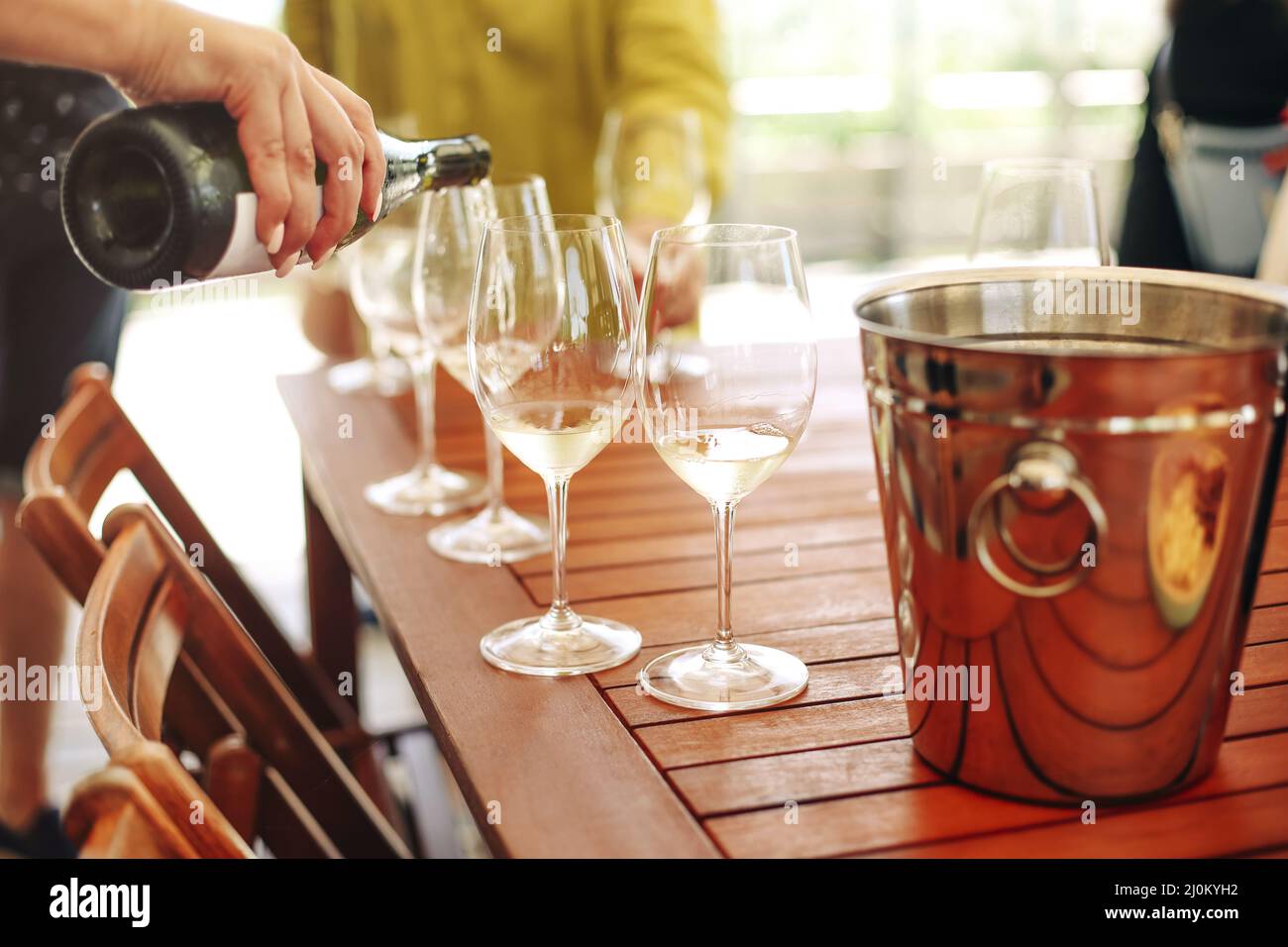 Gläser mit verschiedenen Weinsorten und menschlichen Händen, die Weingläser im Hintergrund halten Stockfoto