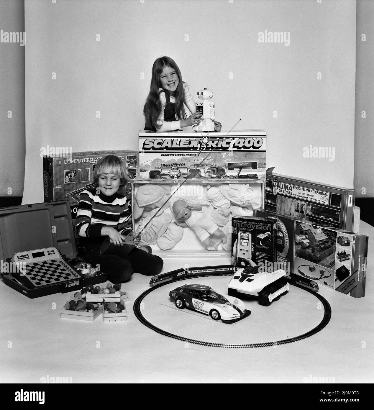 Ein kleiner Junge und ein Mädchen mit einer Auswahl an Kinderspielzeug zu Weihnachten. Dezember 1980. Stockfoto