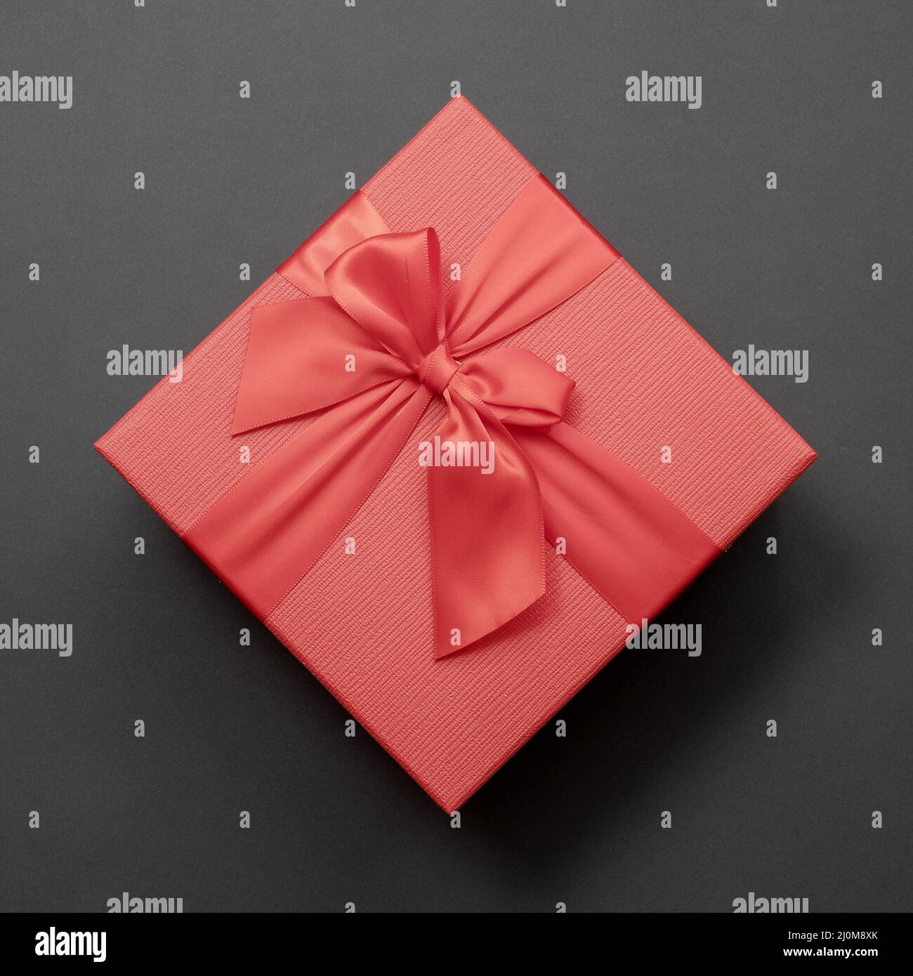 Rote Box mit Schleife auf dunkelgrauem Hintergrund. Draufsicht. Stockfoto