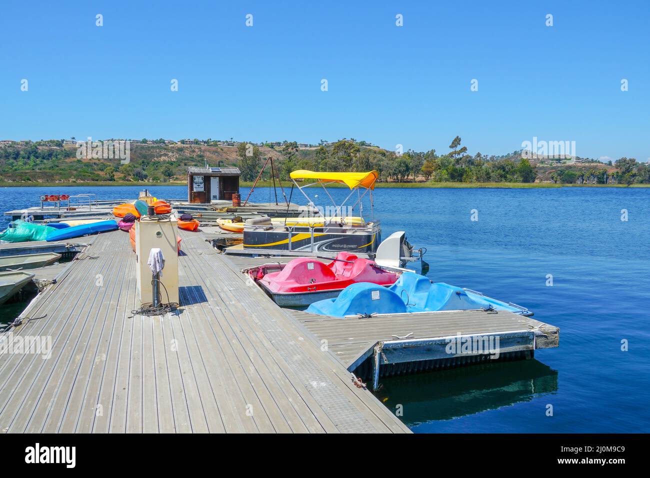 Kleiner Pier mit Tretboot, kleines Motorboot. Stockfoto