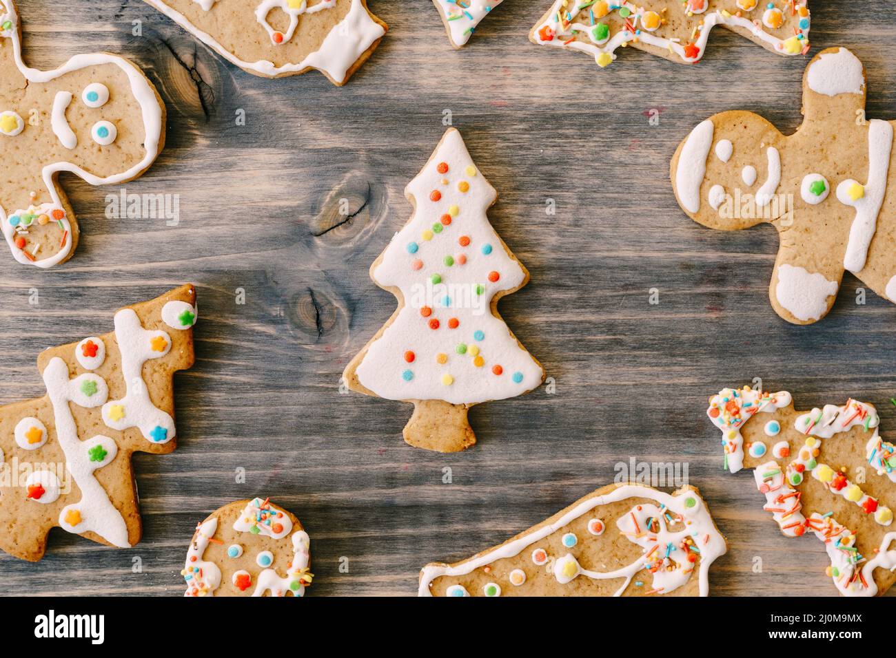 Nahaufnahme von Weihnachts-Lebkuchengebäck auf Holzstruktur. Tannenbäume, kleine Männer und Glocken mit weißer Glasur mit Maultier verziert Stockfoto