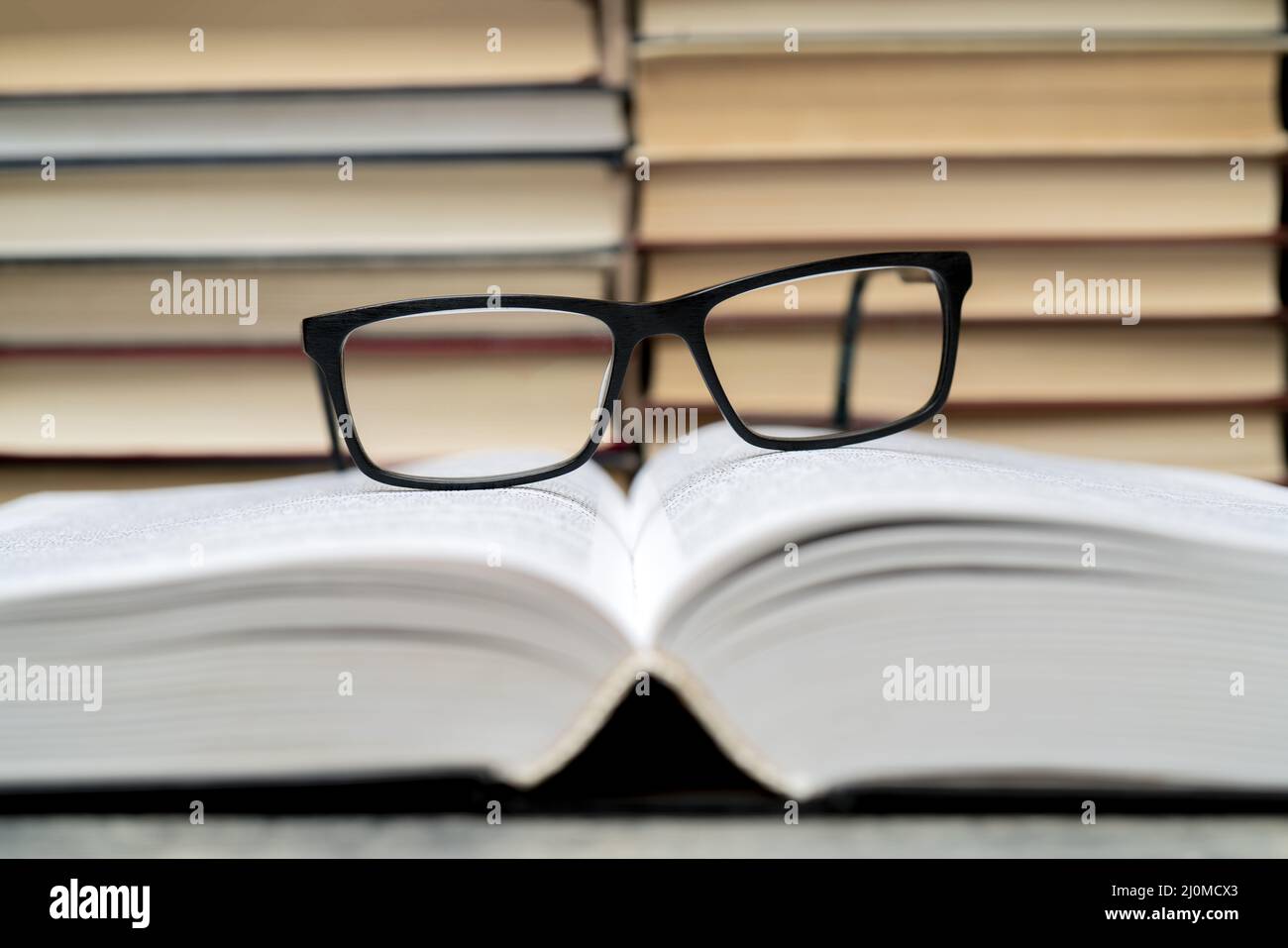 Gläser auf dem Hintergrund der Bücher. Symbol von Wissen, Wissenschaft, Studium, Weisheit. Stockfoto