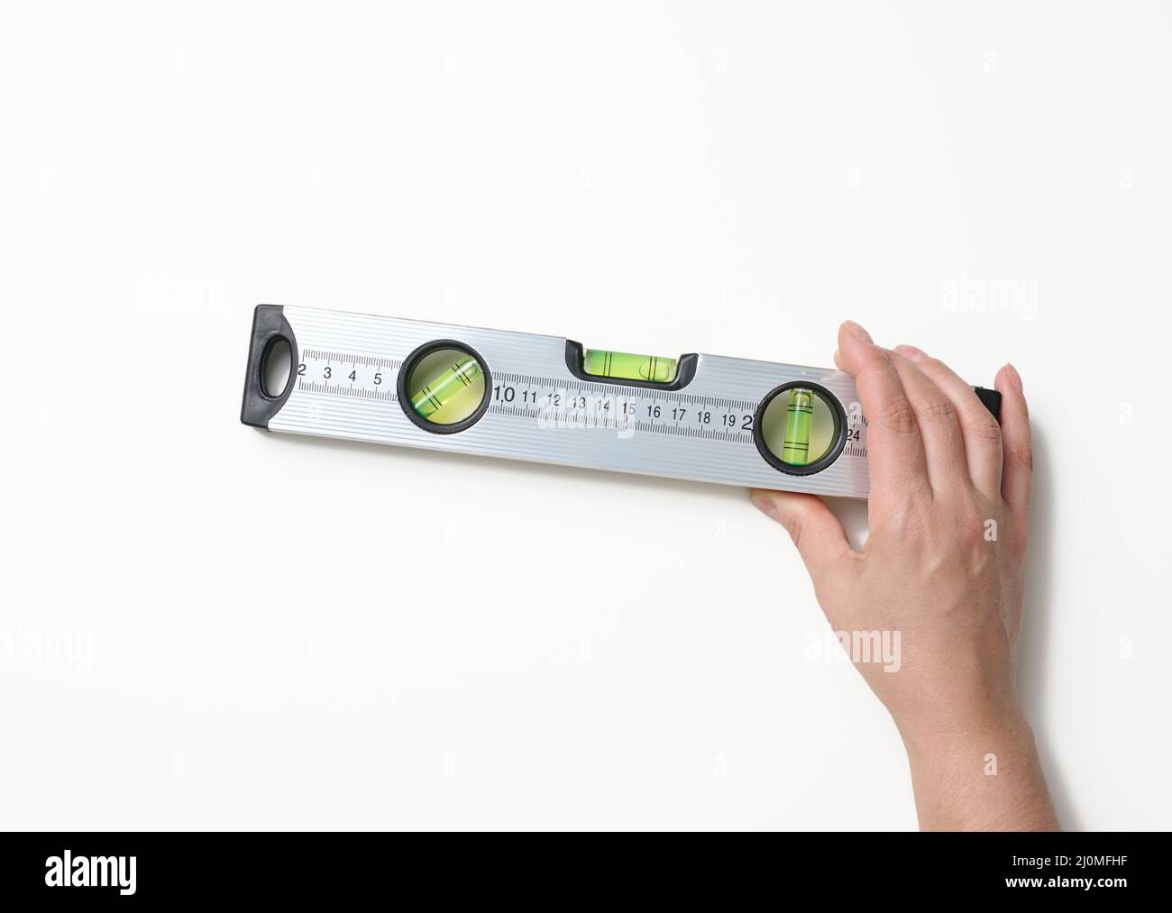 Weibliche Hände halten eine graue metallische Gebäudeebene auf weißem Hintergrund. Messgerät Stockfoto