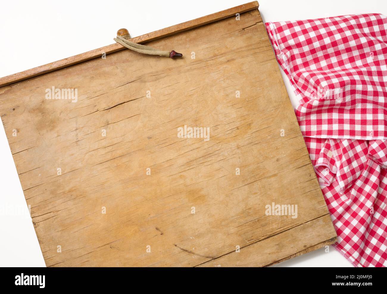 Leere rechteckige Holzküche Schneidebrett und rotes Handtuch in einem weißen Käfig auf einem weißen Tisch, Draufsicht Stockfoto