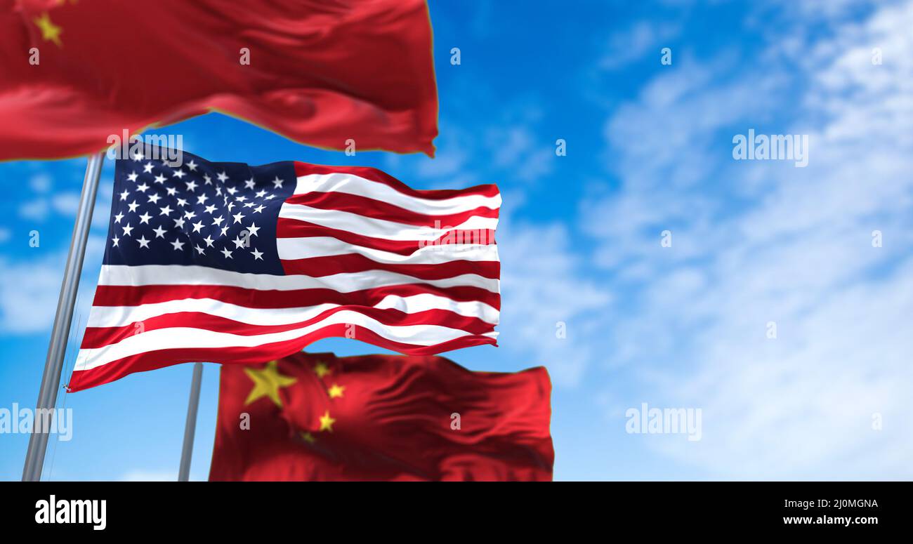 Die Nationalflagge der Vereinigten Staaten winkt zwischen zwei Flaggen Chinas mit klarem Himmel im Hintergrund Stockfoto