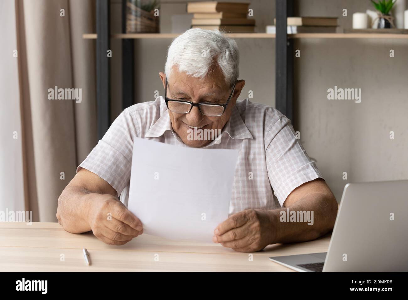 Glücklicher älterer Mann, der Brief mit guten Nachrichten liest, fühlt sich zufrieden Stockfoto