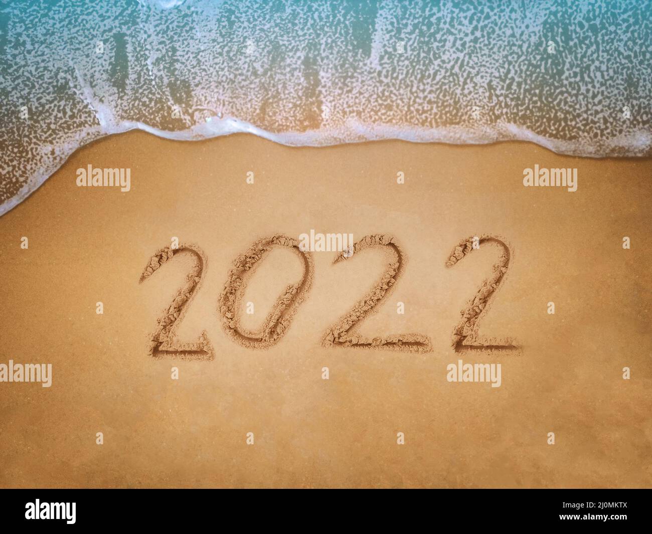 Frohes neues Jahr 2022, Schriftzug am Strand mit Welle und blauem Meer. Zahlen 2022 Jahr an der Küste, Neujahrs-Konzept. Stockfoto