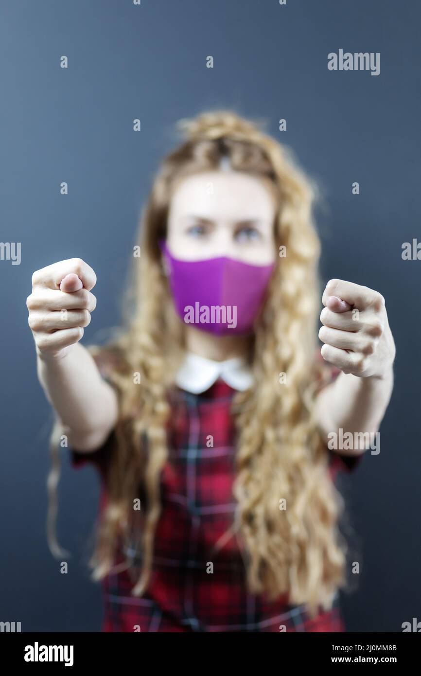 Zwei Feigen werden von einem Mädchen in einer Gesichtsmaske verdreht. Keine Coronavirus-Geste. Konzentrieren Sie sich auf die Hände. Die Dame ist entkokkkkkkkkkk Stockfoto