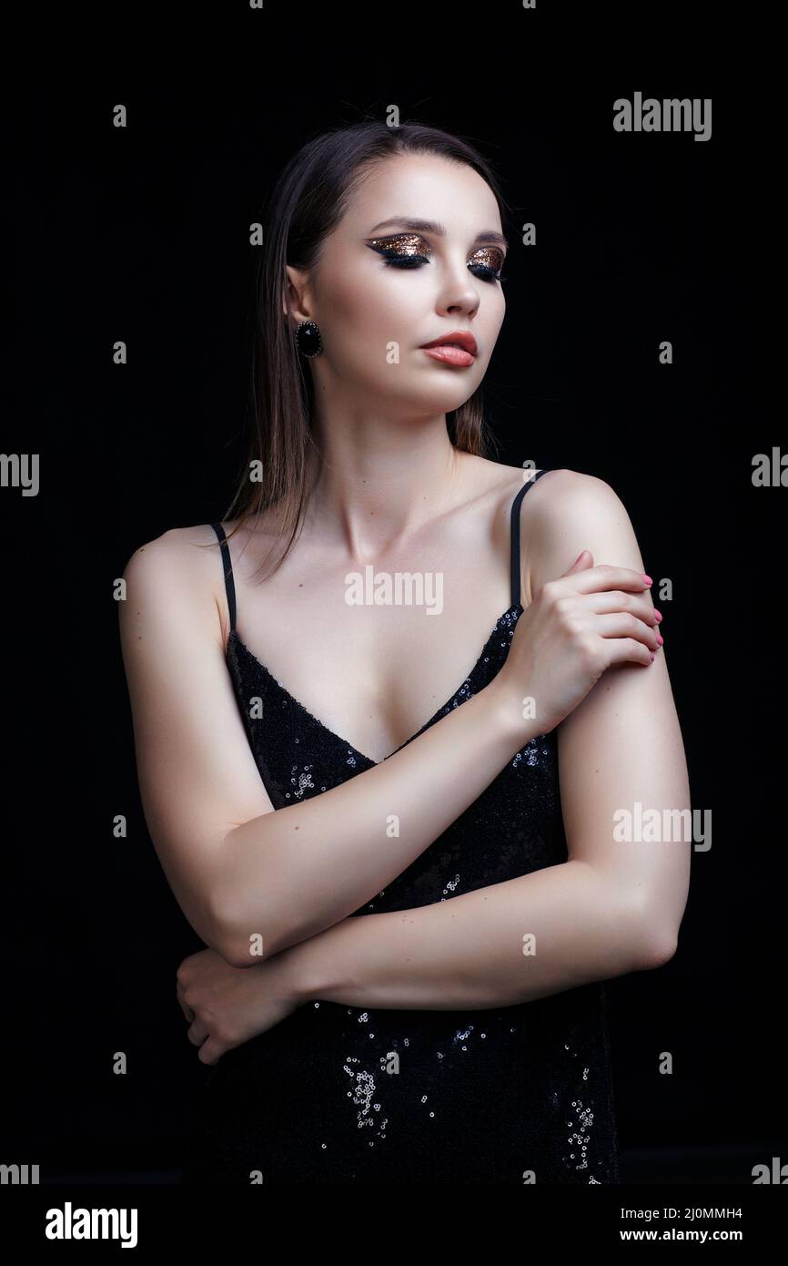 Schöne junge Frau in schwarzem Kleid mit glänzendem Gesicht Make-up. Stockfoto