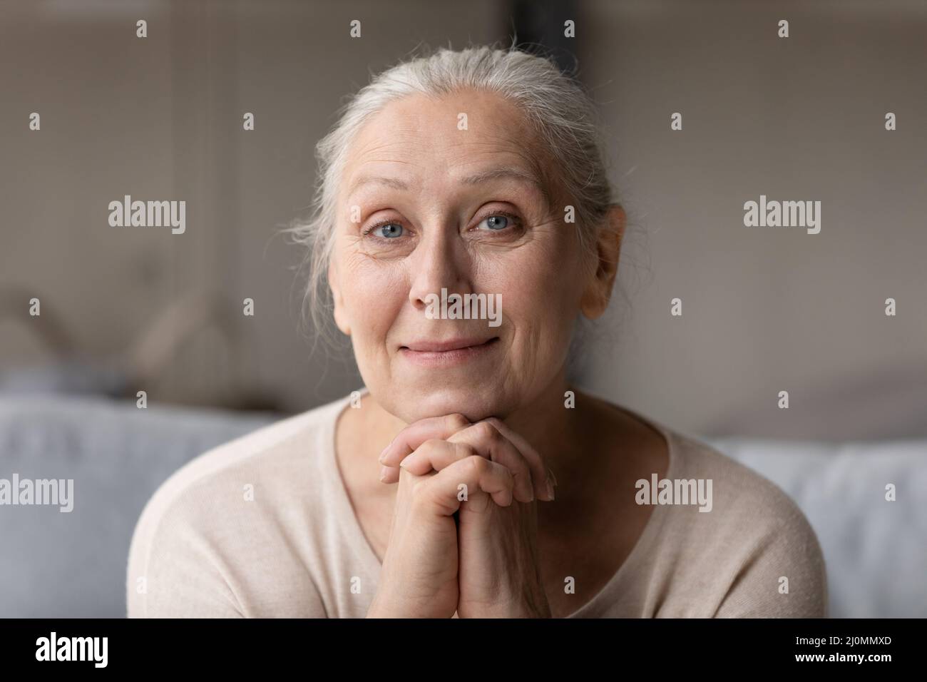 Friedliche ältere Frau lächelt und starrt auf die Kamera, ein Porträt mit Kopfschuss Stockfoto