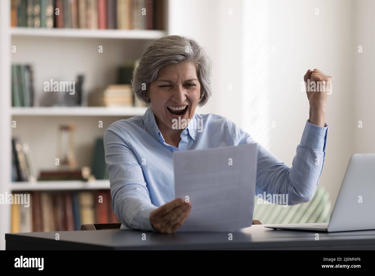 Ältere Geschäftsfrau liest Dokumente, schreit vor Freude, feiert gute Nachrichten Stockfoto