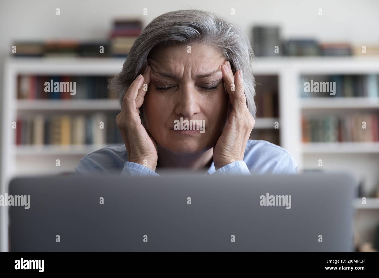 Ältere Geschäftsfrau berührt Tempel leidet an Migräne, Nahaufnahme Stockfoto