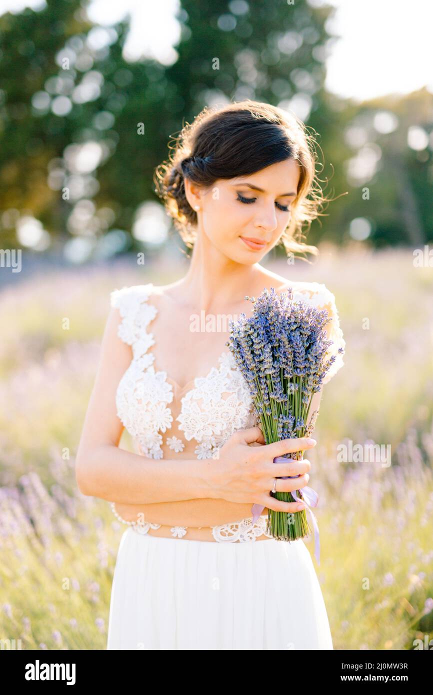 Sibenik, Kroatien - 05.06.17: Die Braut in einem weißen Spitzenkleid hat ihre Arme über ihre Brust gekreuzt und hält einen Strauß Lavendel Stockfoto