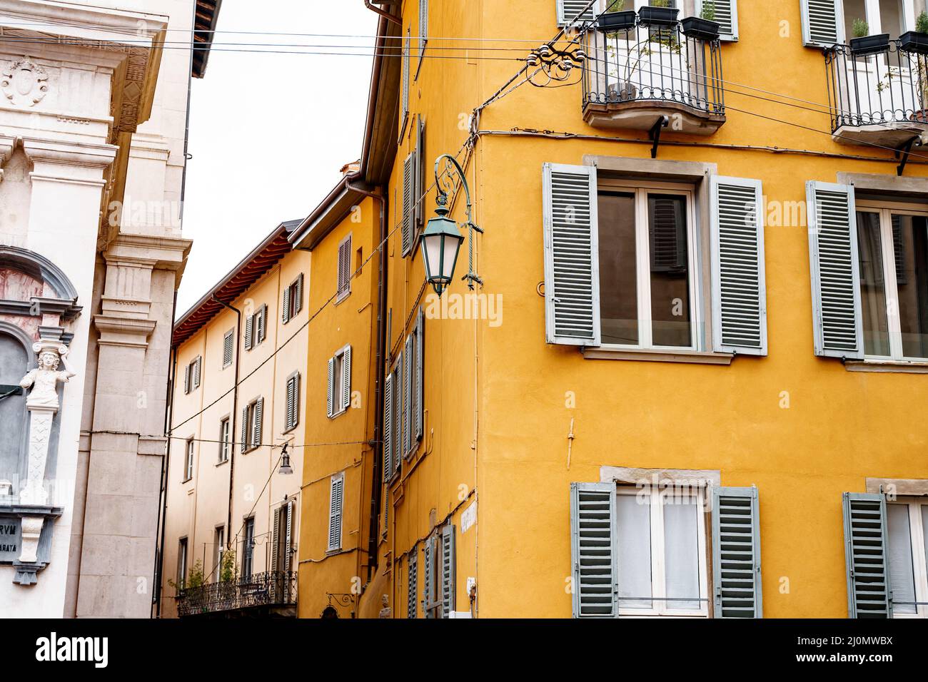 Metalllaterne an der Ecke eines alten Hauses mit versperrten Fenstern. Bergamo, Italien Stockfoto