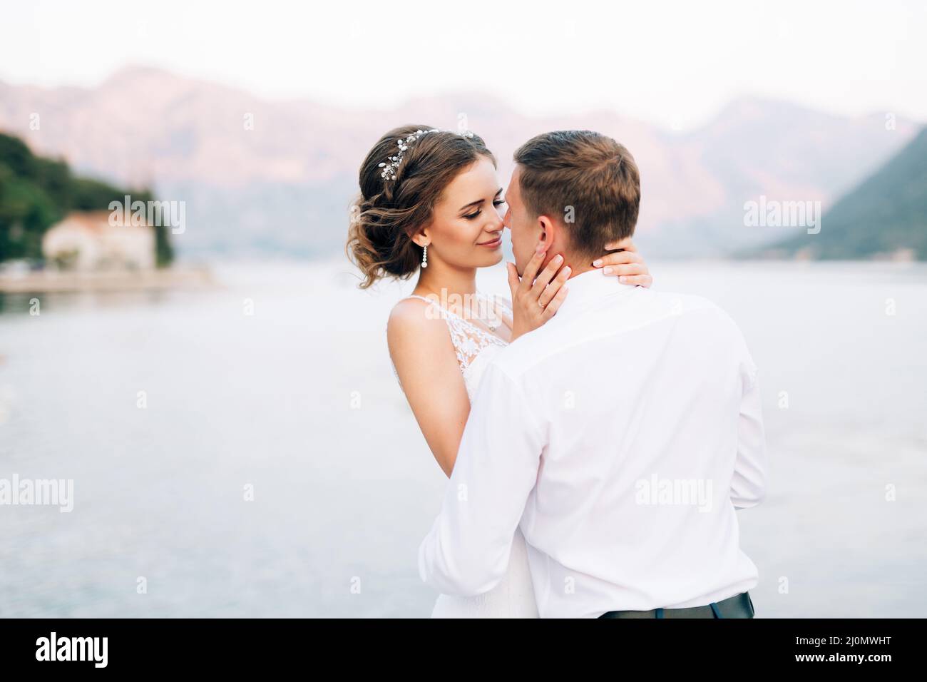 Kotor, Montenegro - 20.06.17: Braut umarmt und küsst sich fast vor der Kulisse der Berge und des Meeres. Nahaufnahme Stockfoto