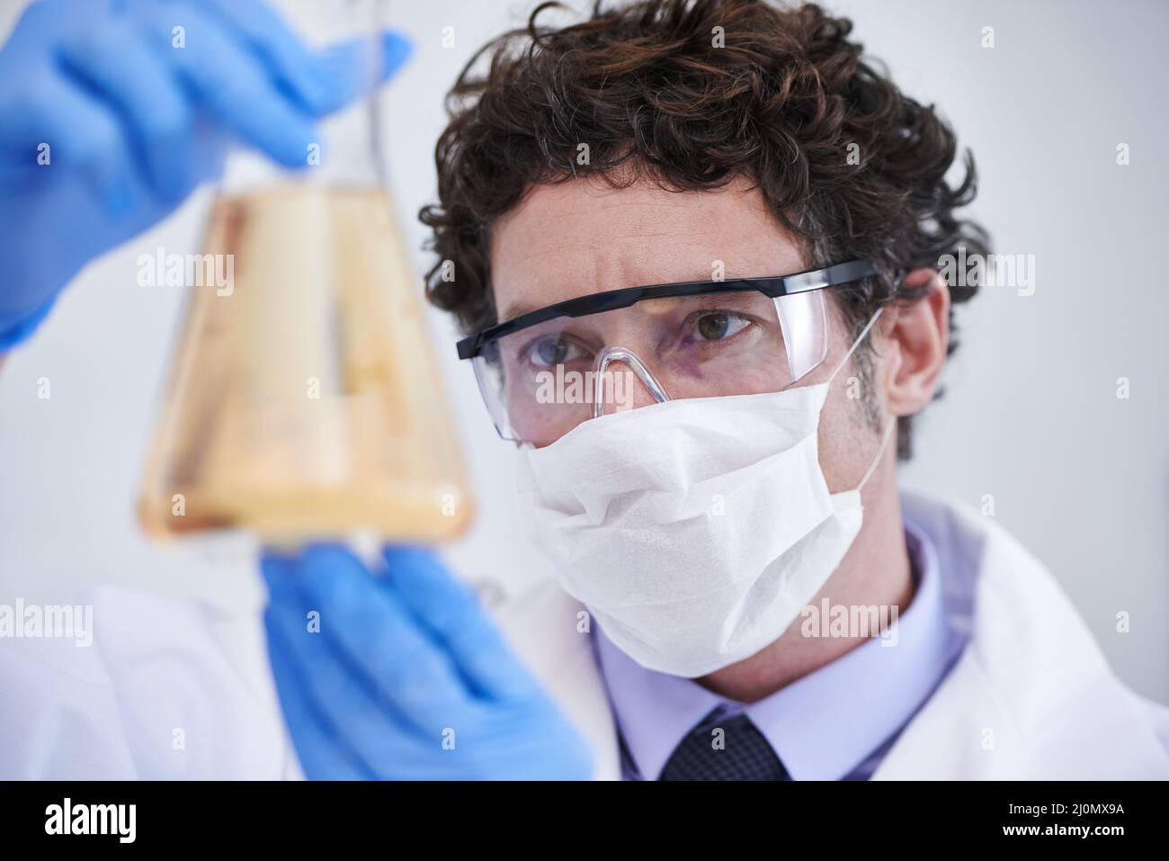 Was könnte das bedeuten? Ein abgeschnittenes Bild eines Wissenschaftlers, der eine mit Flüssigkeit gefüllte Flasche untersucht. Stockfoto
