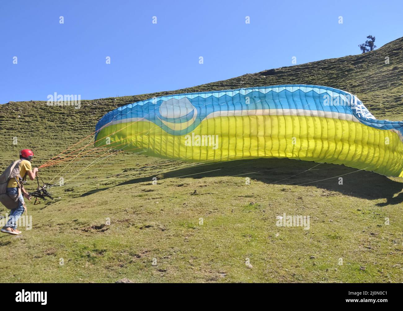 Ein nicht identifizierter männlicher Gleitschirm, der den Fallschirm für den Flug in den Himmel vorbereitet Stockfoto