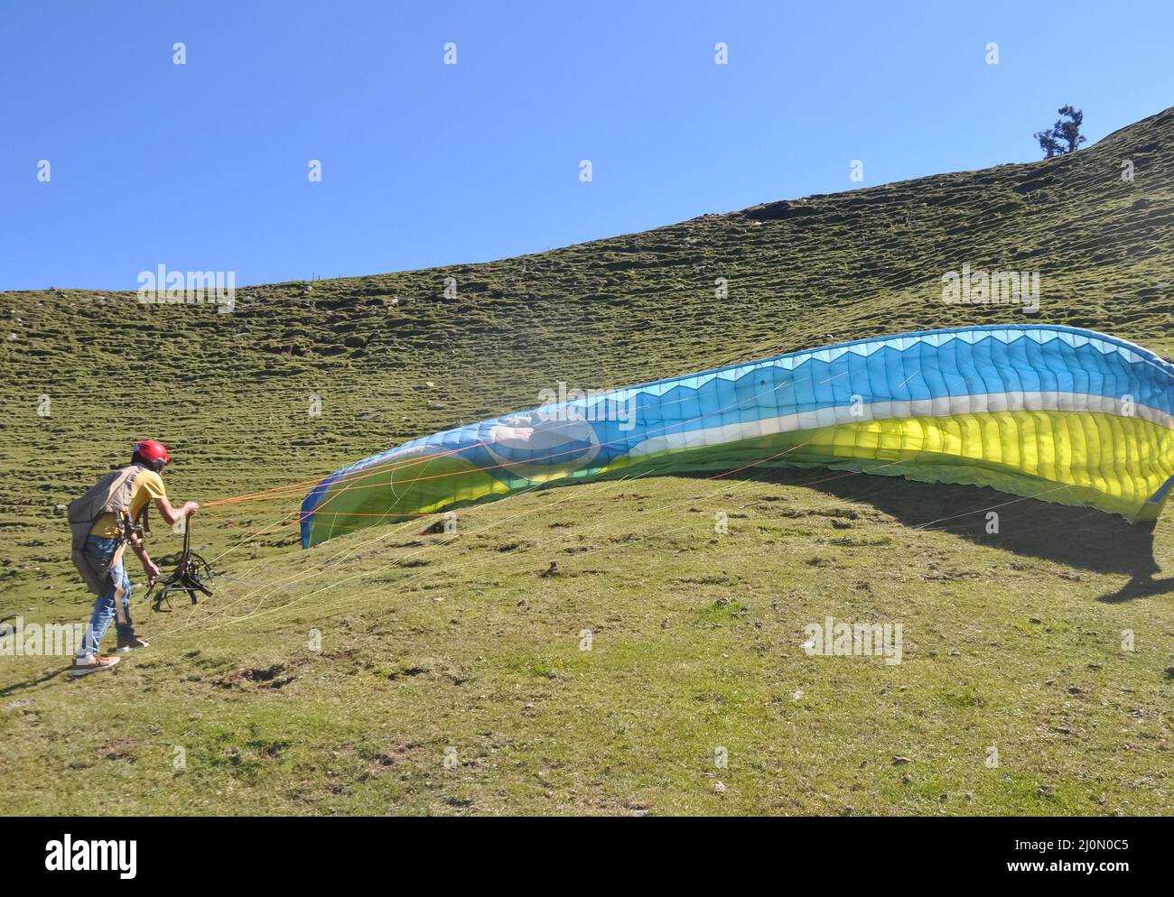 Ein nicht identifizierter männlicher Gleitschirm, der den Fallschirm für den Flug in den Himmel vorbereitet Stockfoto