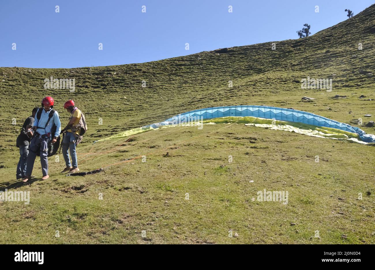 Mandi, Himachal Pradesh, Indien - 10 16 2021: Gleitschirme helfen einem Touristen bei der Anpassung des Fallschirms an die Vorbereitung auf das Gleitschirmfliegen im Berg Stockfoto