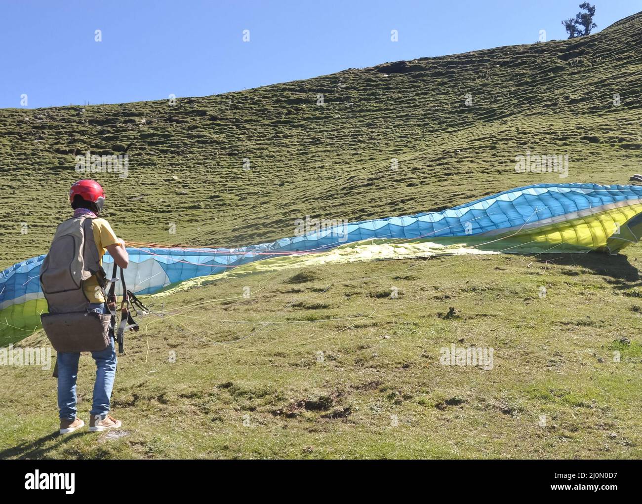 Ein nicht identifizierter männlicher Gleitschirm, der den Fallschirm für den Flug in den Himmel vorbereitet Stockfoto