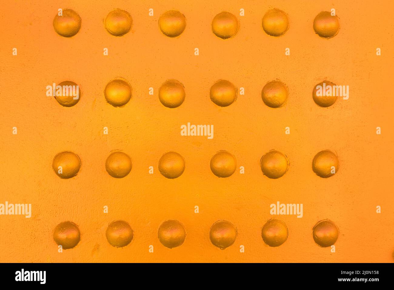 Nieten auf Metall mit einem Hauch von warmen Farben Hintergrund Stockfoto