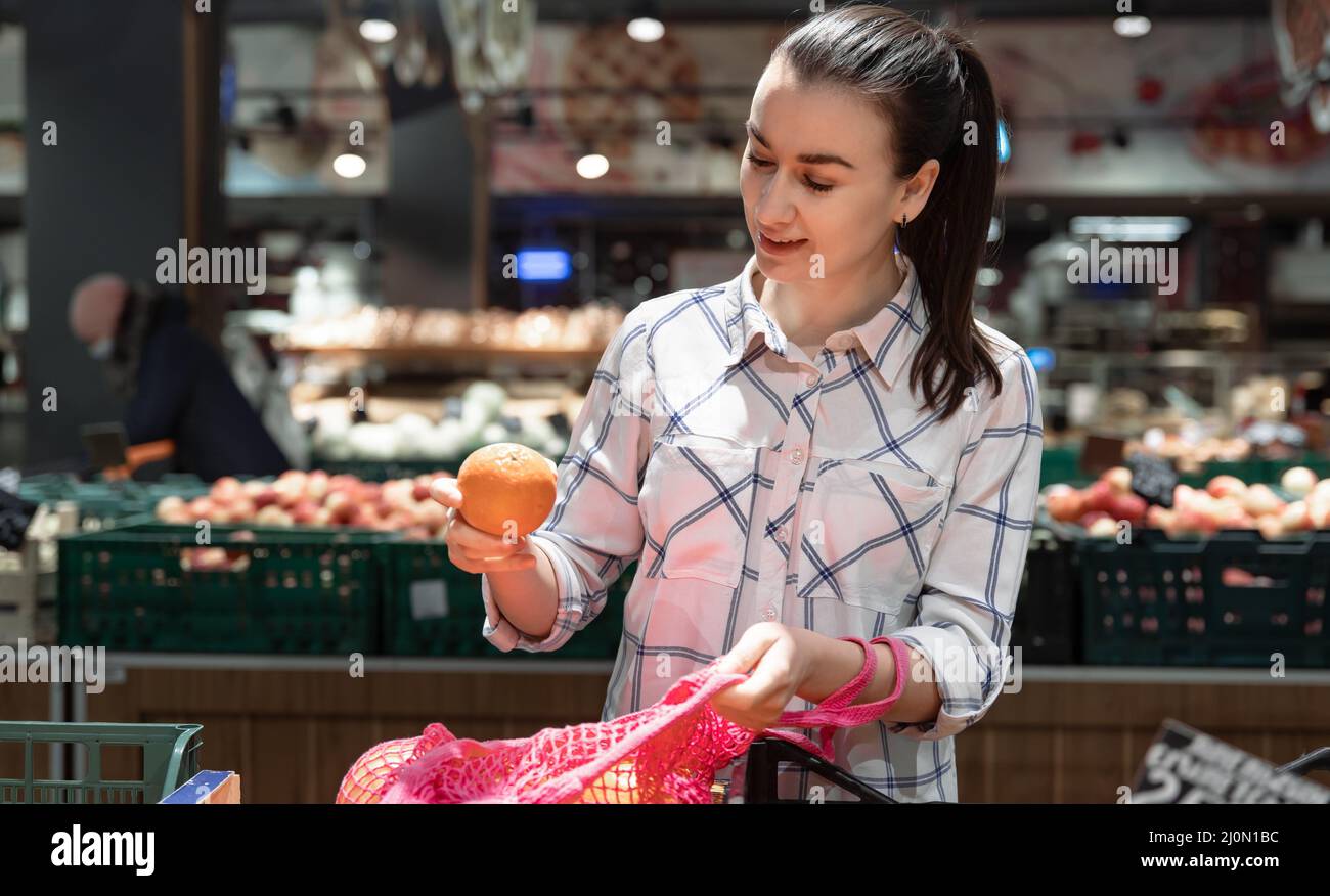 Eine junge Frau wählt Früchte in einem Supermarkt. Stockfoto