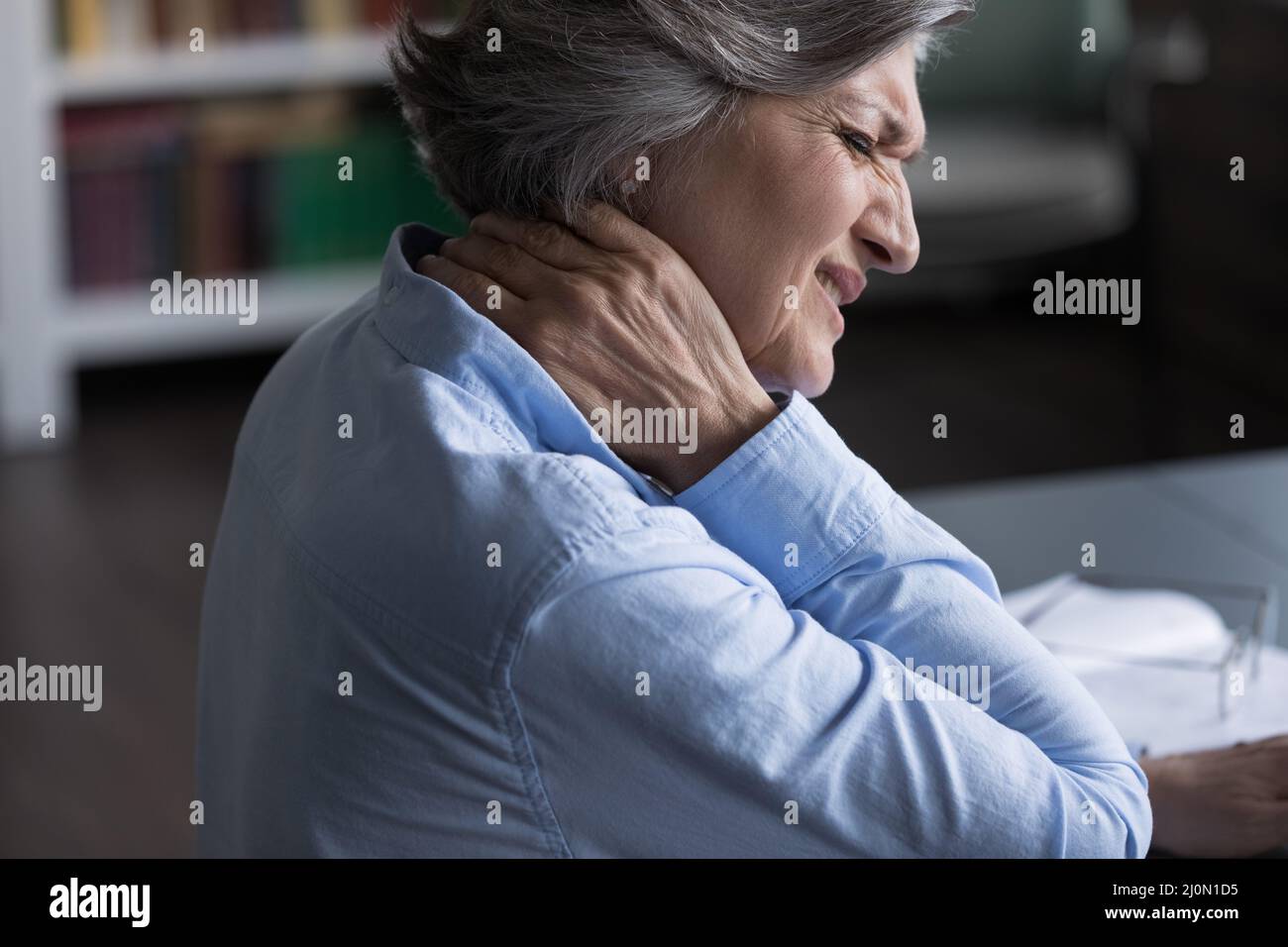 Nahaufnahme einer Frau mittleren Alters, die an Nackenschmerzen leidet Stockfoto
