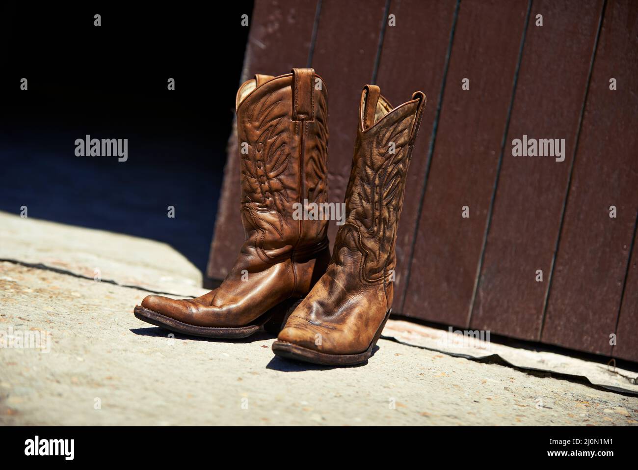 Durch harte Arbeit getragen. Aufnahme eines Paares Cowboystiefel vor einer Scheune. Stockfoto