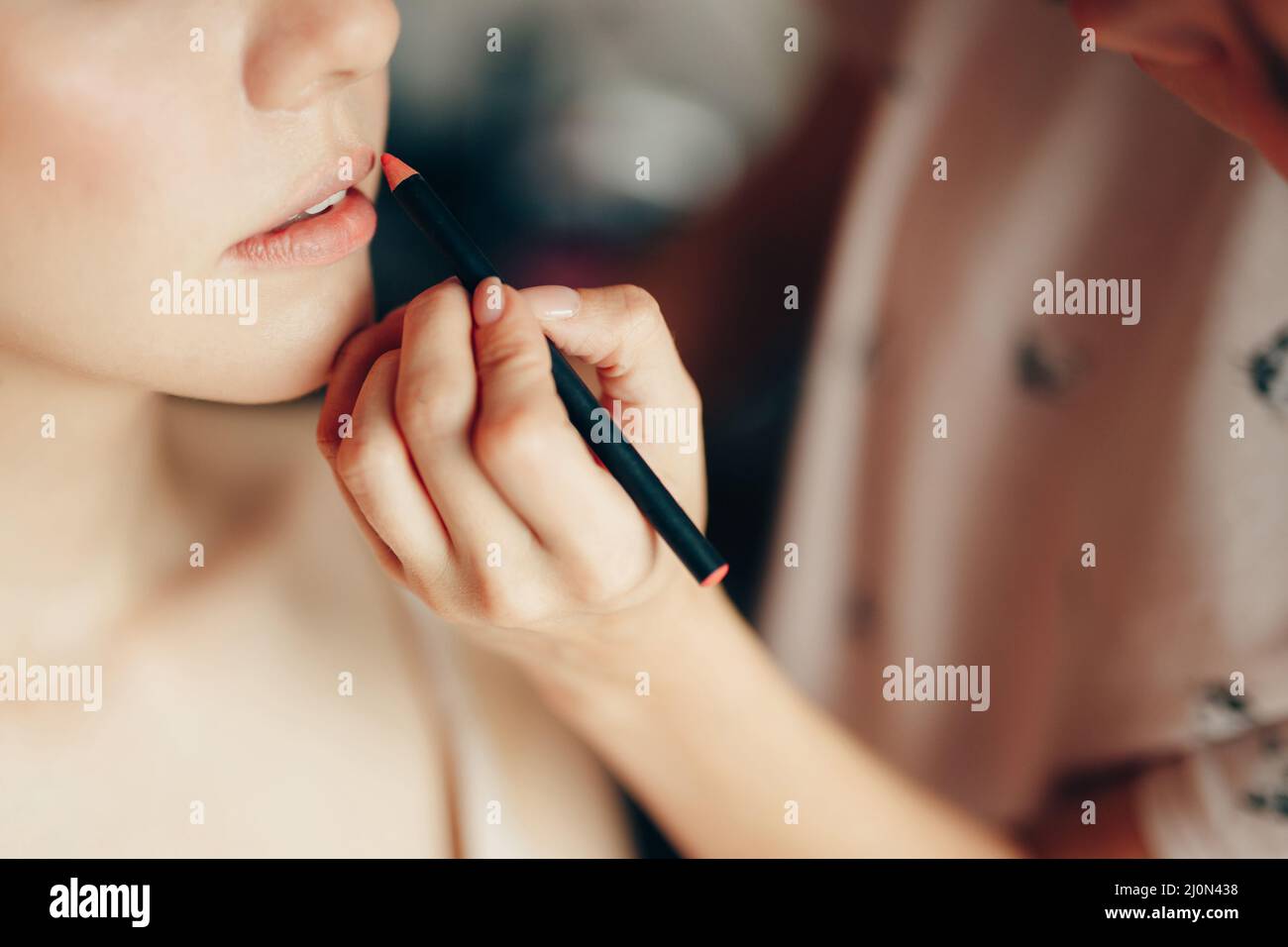 Makeup-Künstler malt die Lippen des Kunden mit einem Bleistift. Nahaufnahme Stockfoto