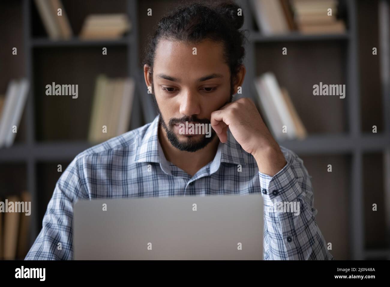Fokussierter afroamerikanischer Student mit Laptop in der Bibliothek Stockfoto