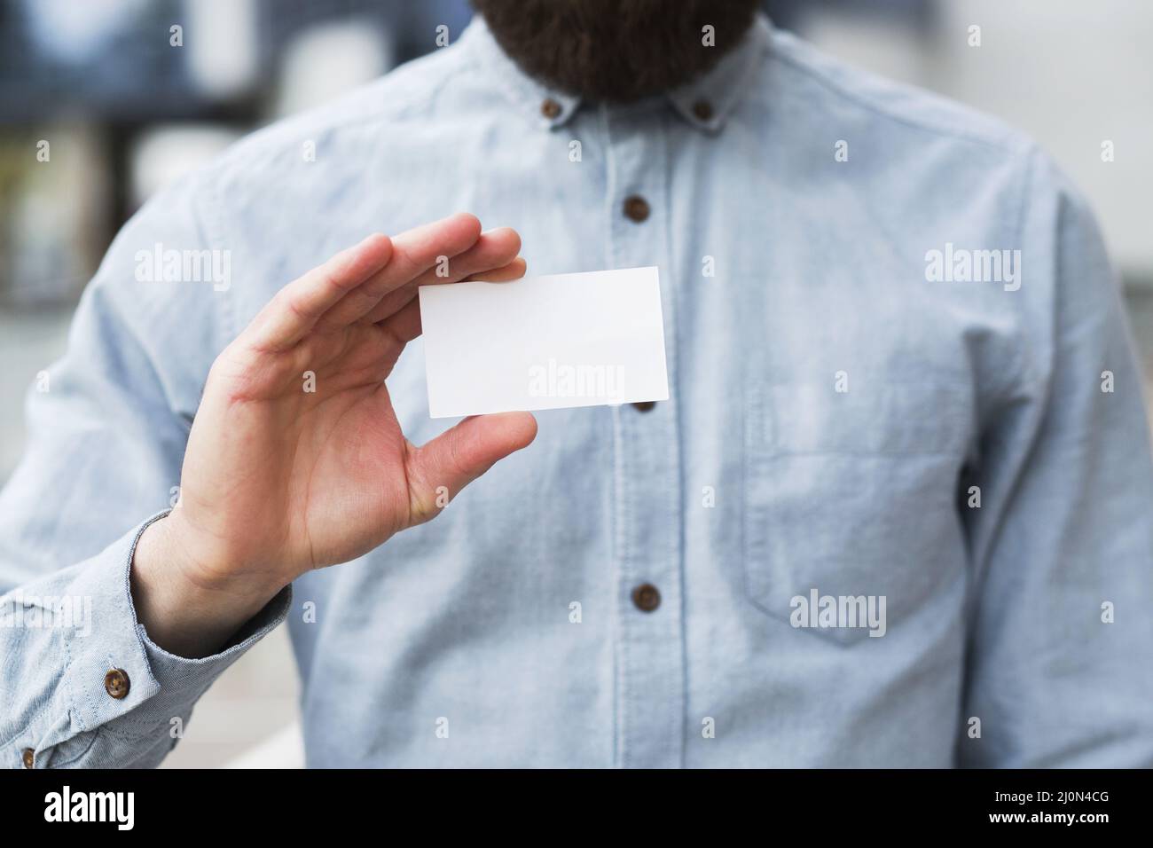 Nahaufnahme der Hand eines Geschäftsmannes, der eine weiße, leere Visitenkarte zeigt Stockfoto