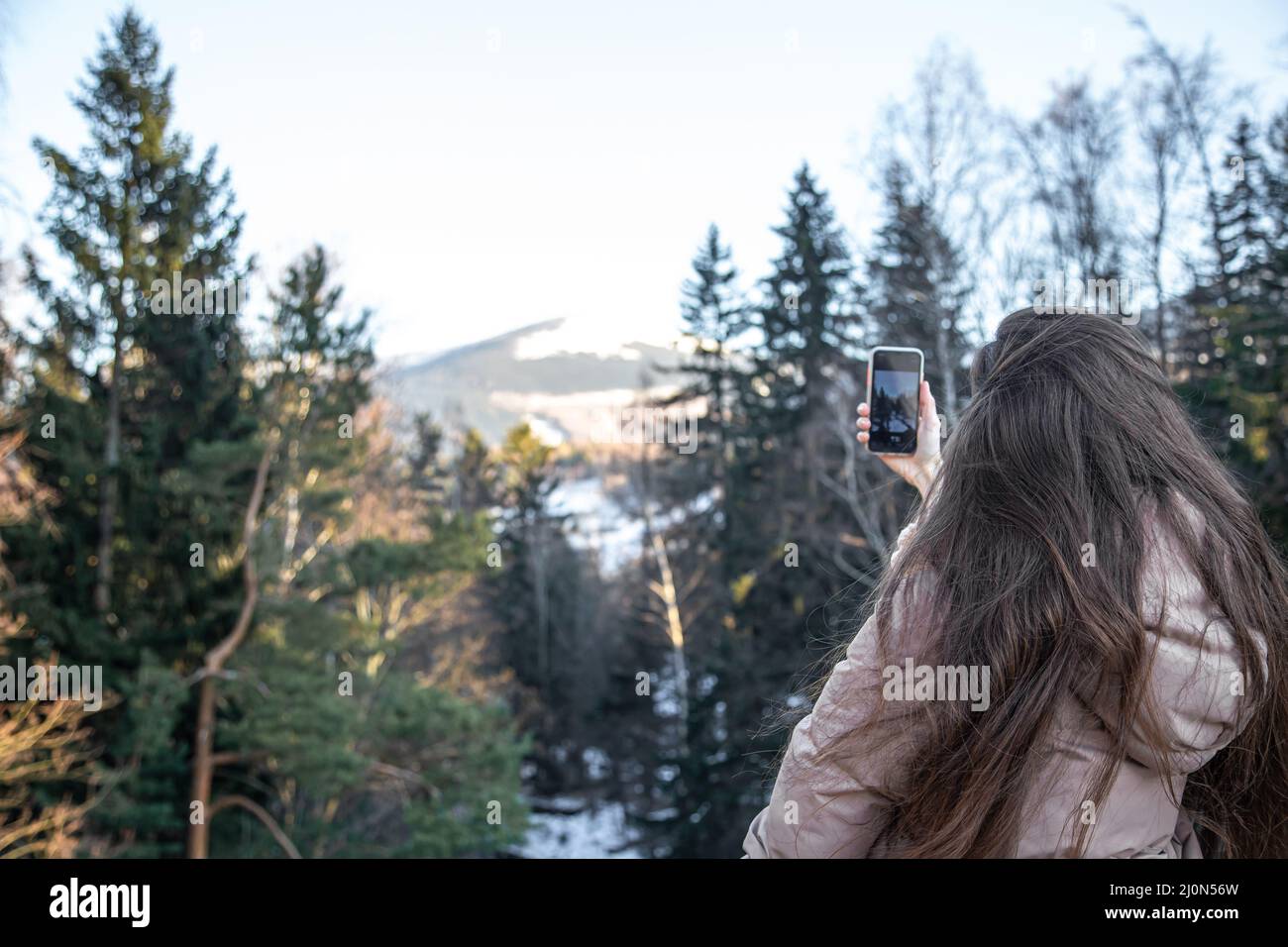 Eine junge Frau fotografiert die Berge mit einem Smartphone. Stockfoto