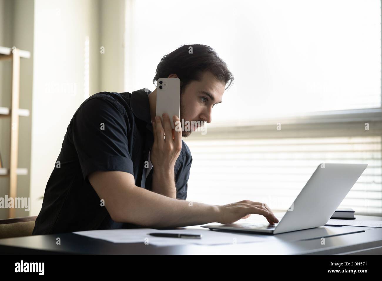 Seriös fokussierter, vielbeschäftigter Manager, der einen Anruf beim Kunden führt Stockfoto