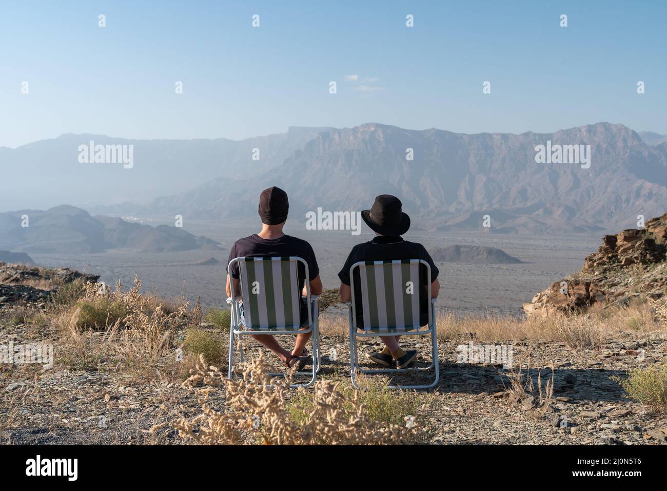 Ein Mann und eine Frau sitzen auf Lagerstühlen mit Blick auf die Gubrah Bowl in Oman Stockfoto