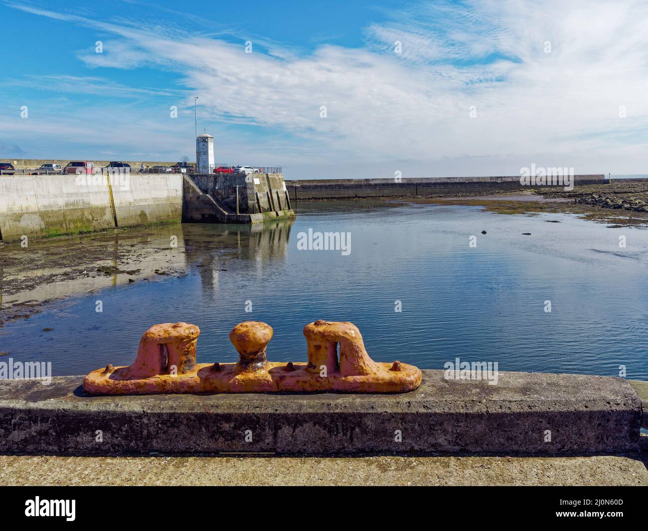 Das Navigationslicht und der Eingang in den Hafen von Seahouses, aufgenommen vom inneren Kai, mit einem gelben Seilzug im Vordergrund. Stockfoto