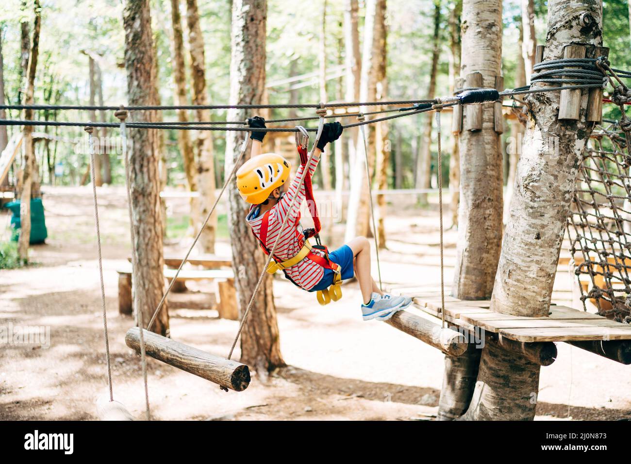 Boy in einem Sicherheitsgurt springt über die Querbalken auf der Agility Bridge Stockfoto