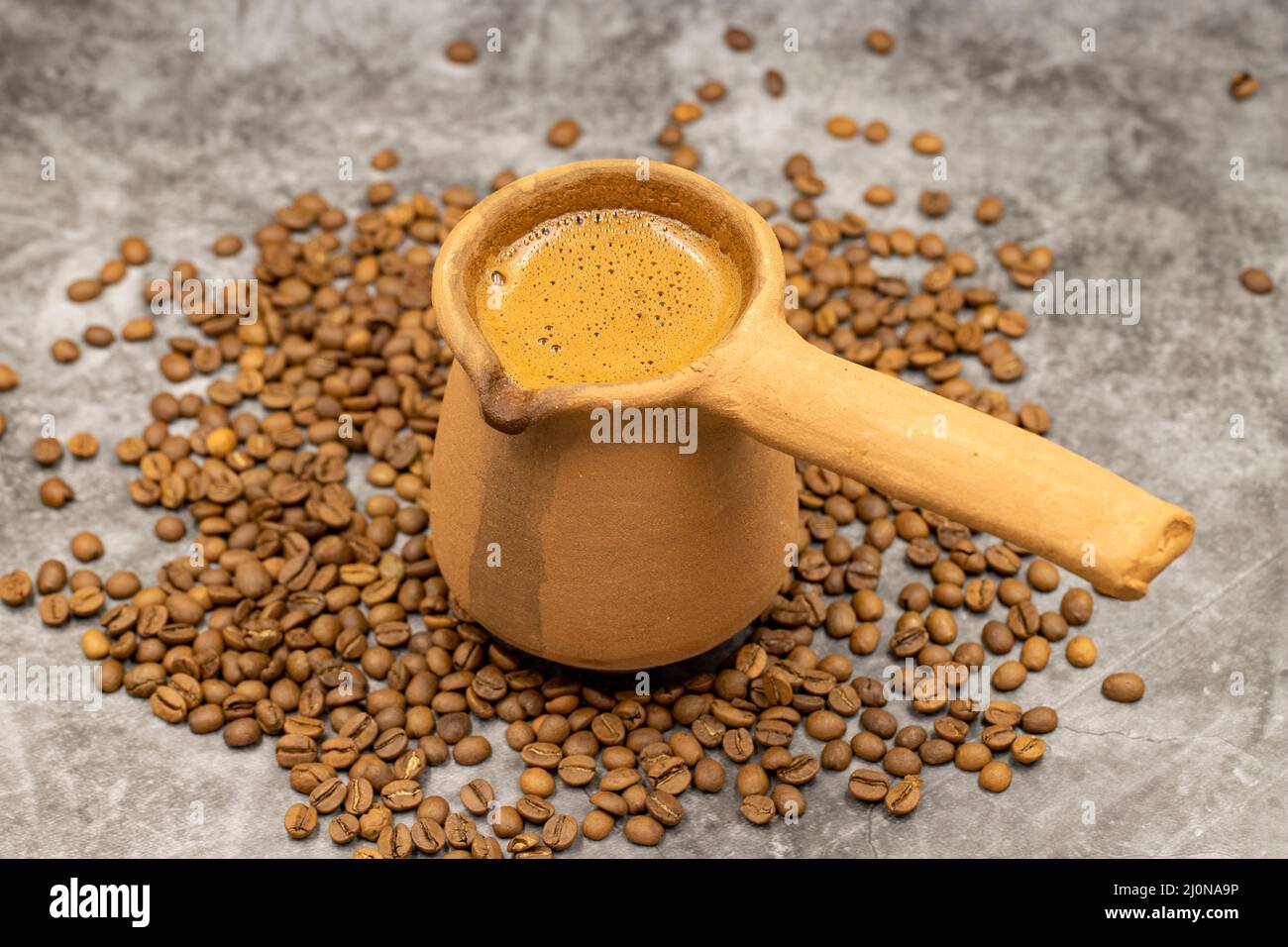 Türkischer Kaffee in einer irdenen Kanne auf dunklem Hintergrund. Nahaufnahme Stockfoto