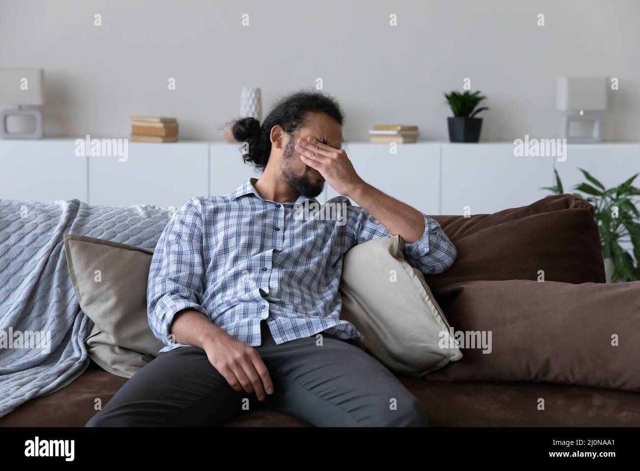 Gestresster tausendjähriger afrikanischer Mann, der sich erschöpft fühlt, starke Kopfschmerzen Stockfoto