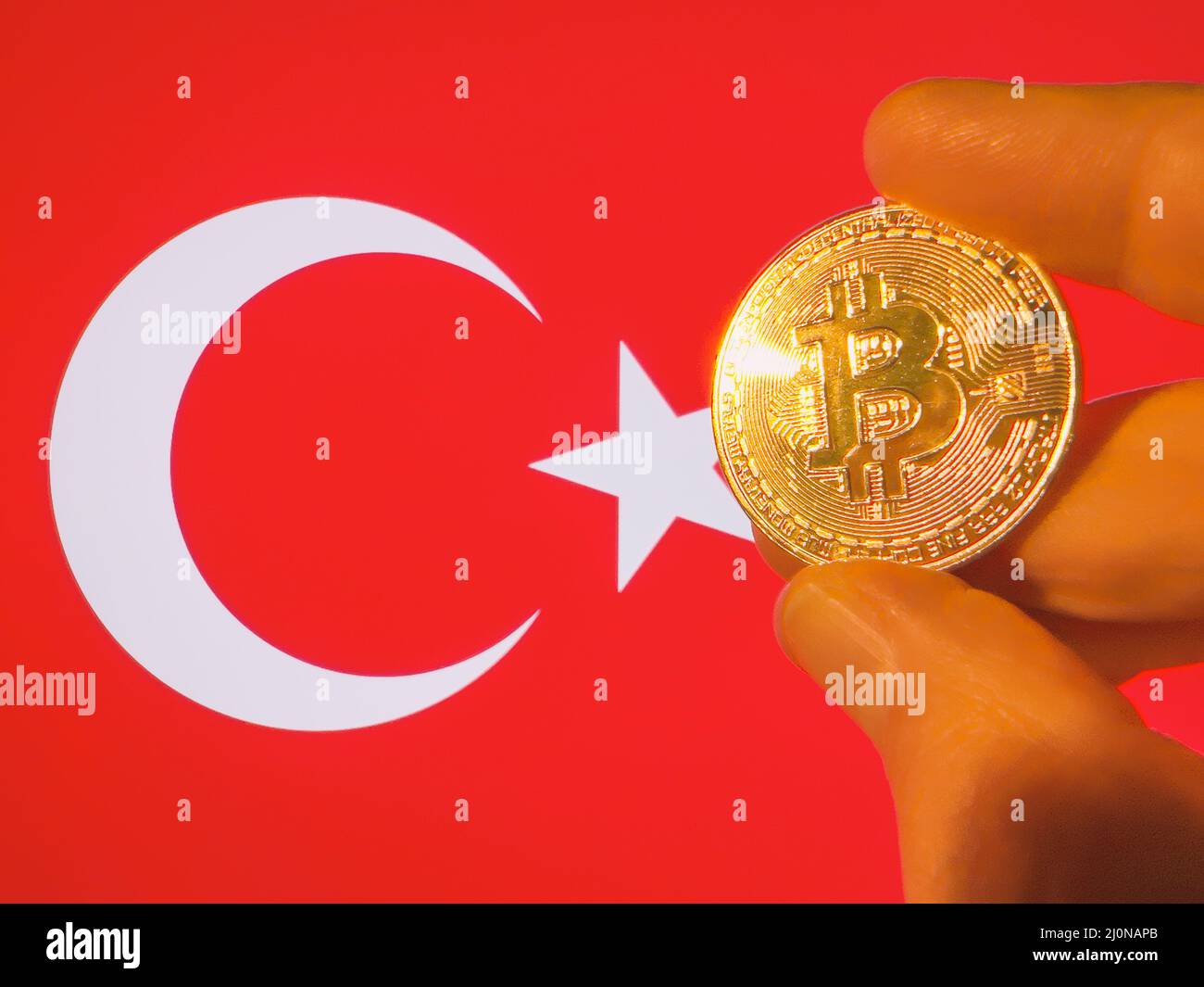 Mit einem physischen goldenen Bitcoin über der türkischen Flagge. Die Türkei als Investor in Kryptowährung und Blockchain-Technologie. Finanzieller Hintergrund Stockfoto