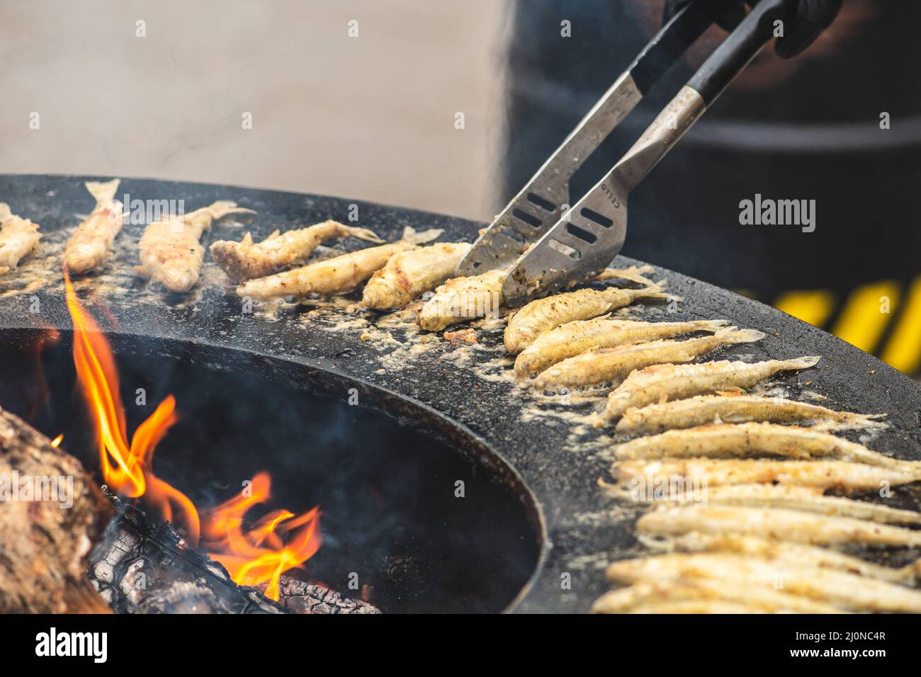 Das Zubereiten von traditionellem, schmackhaftem gebratenem europäischem Fisch, der auf einem Straßenmarkt am offenen Feuer gekocht wird, verzehrfertig, Street Food in Vilnius Stockfoto