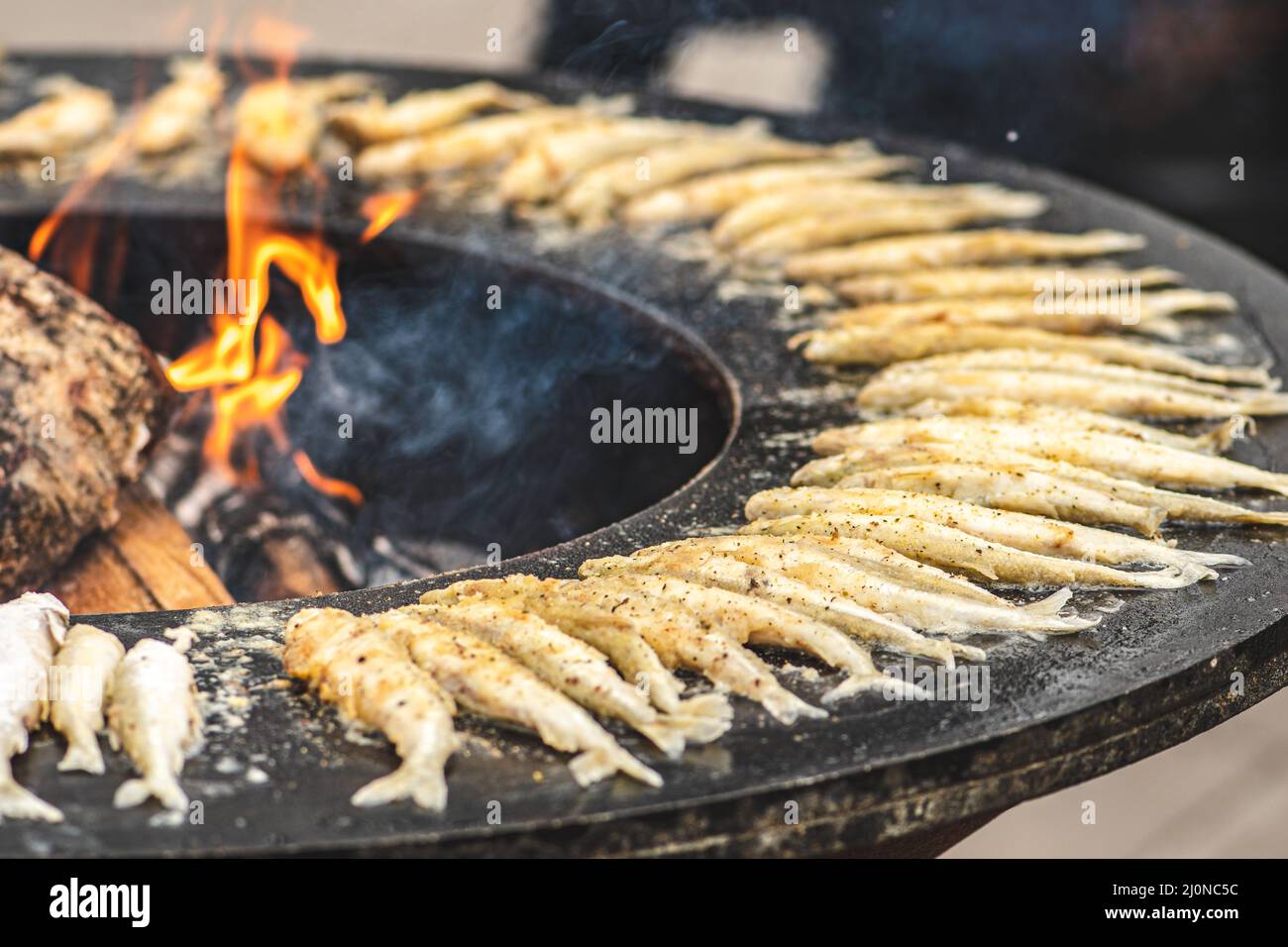 Das Zubereiten von traditionellem, schmackhaftem gebratenem europäischem Fisch, der auf einem Straßenmarkt am offenen Feuer gekocht wird, verzehrfertig, Street Food in Vilnius Stockfoto