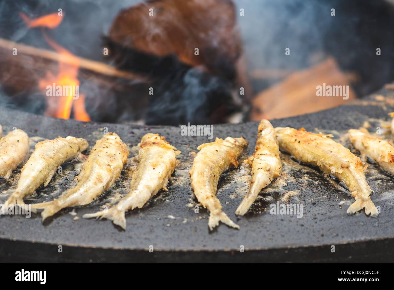Das Zubereiten von traditionellem, schmackhaftem gebratenem europäischem Fisch, der auf einem Straßenmarkt am offenen Feuer gekocht wird, verzehrfertig, Street Food in Vilnius Stockfoto
