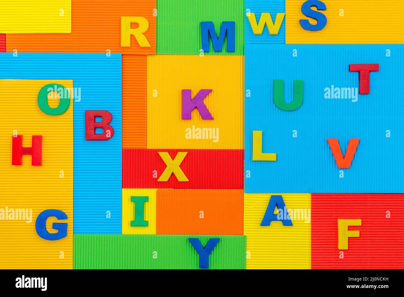 Plastikbuchstaben auf dem bunten Papierhintergrund Stockfoto