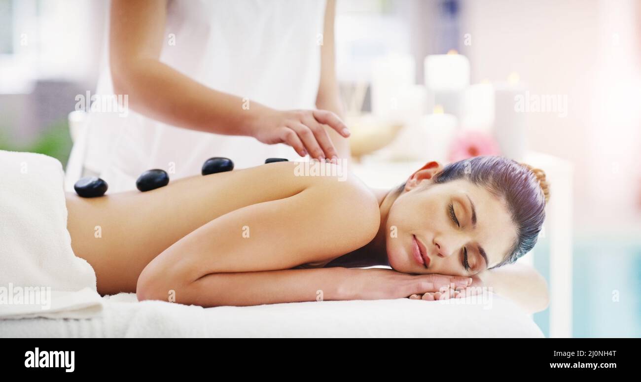 Es ist ein Ort, um das Gleichgewicht wiederherzustellen. Aufnahme einer jungen Frau, die in einem Spa eine Hot-Stone-Massage bekommt. Stockfoto