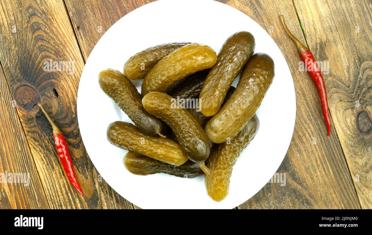 Hausgemachte Salzgurken mit Chilli auf dem Teller auf Holzboden. Häusliche Erhaltung. Selektiver Fokus. Blick von oben, Essen von oben. Nahaufnahme. Stockfoto
